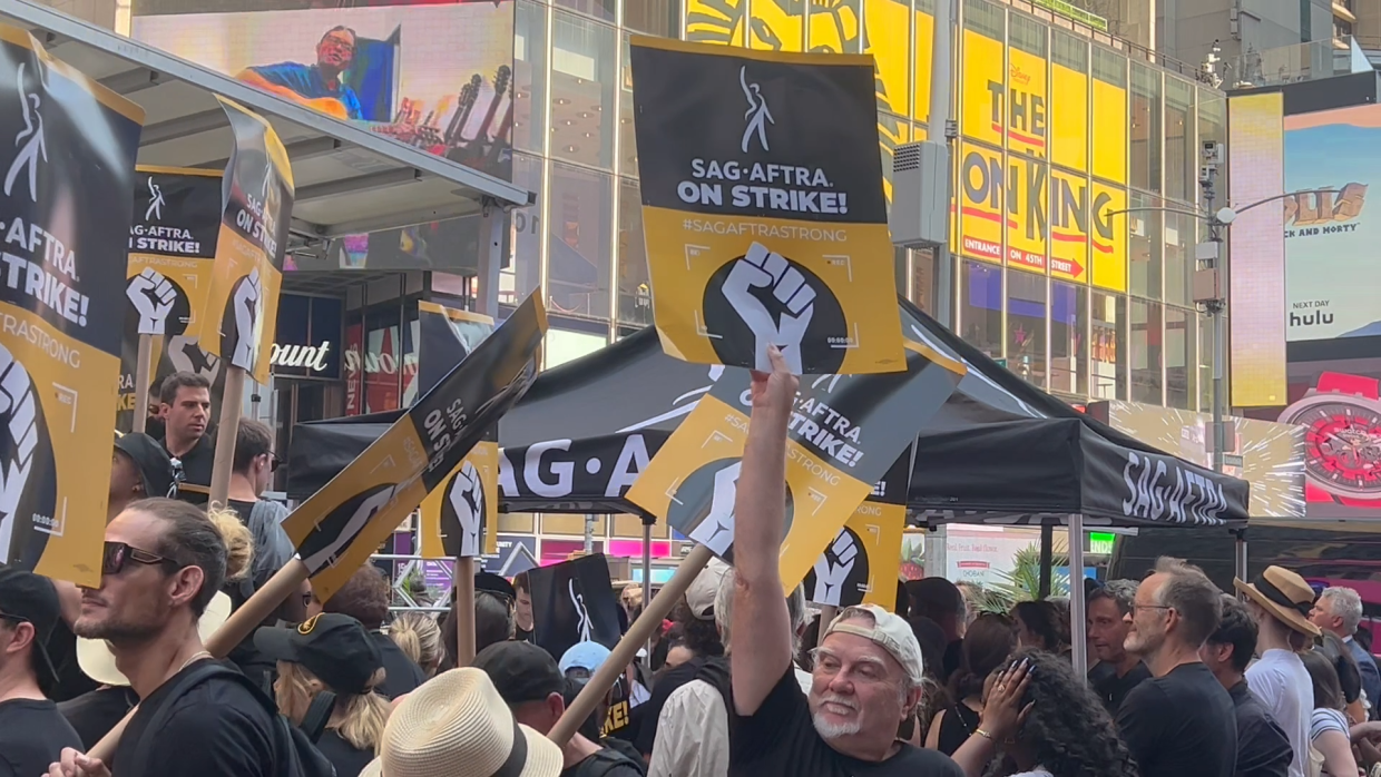 Supporters holding SAG-AFTRA strike signs in Times Square, highlighting the demand for fair contracts.