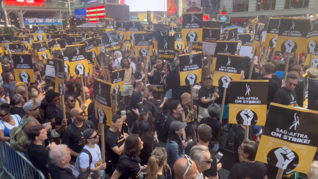 Large crowd of SAG-AFTRA supporters holding strike signs in Times Square during the 2023 rally for fair contracts.