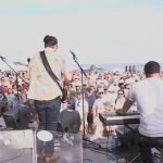 The Allmost Brothers band performing on the Jambalaya Stage at the Great South Bay Music Festival, with a crowd of festival-goers in the background.