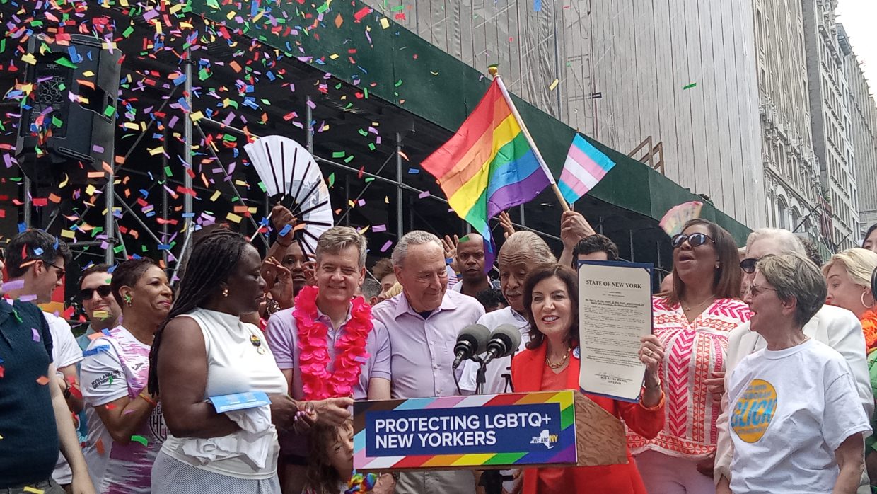 Governor Kathy Hochul speaking at the 2023 NYC Pride Parade, surrounded by LGBTQ+ advocates and confetti.