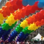 Vibrant rainbow balloons arching over the streets during the 2023 NYC Pride Parade.