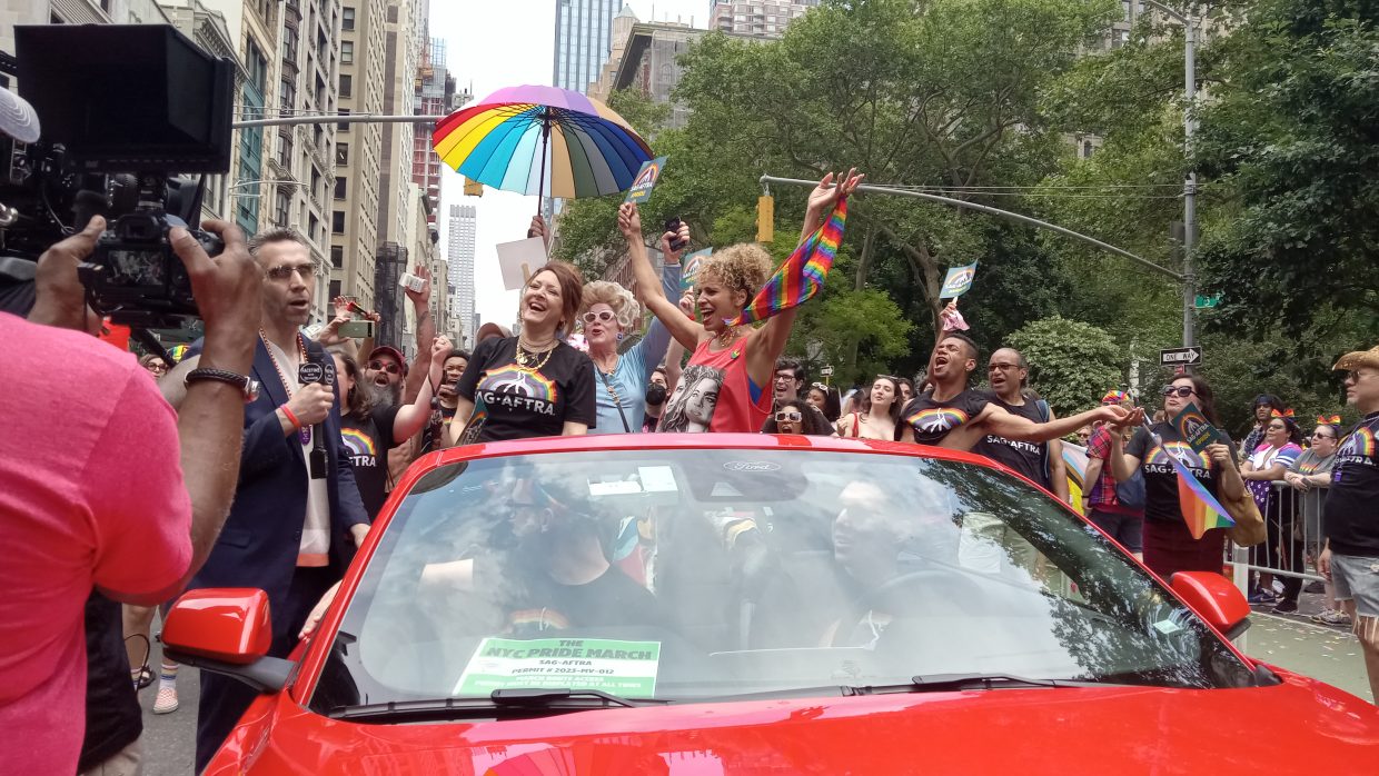 SAG-AFTRA members celebrating in a red convertible during the 2023 NYC Pride Parade.