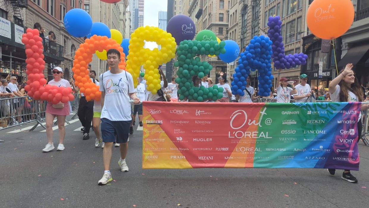 L’Oréal group marching with a colorful balloon display and banner during the 2024 NYC Pride Parade.