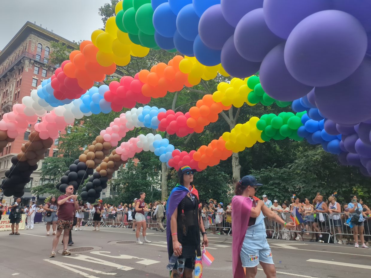Colorful rainbow balloons arching over participants during the 2024 NYC Pride Parade.